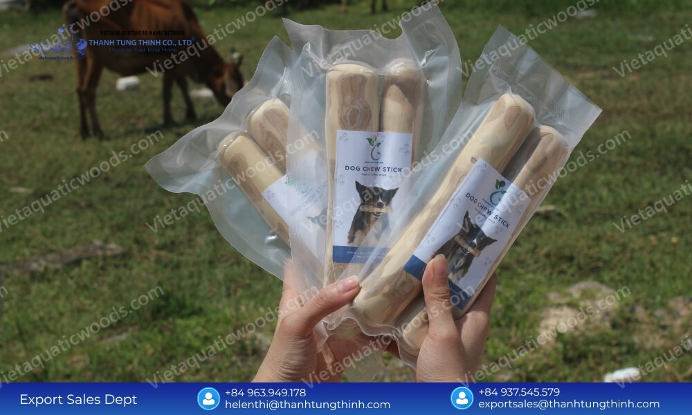 Vacuum sealed organic coffee wood chews wholesale products with branded dog labels held outdoors in a rural pasture setting