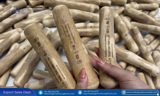 A hand holding a custom laser engraved product from a batch of bulk coffee wood chew sticks assorted sizes